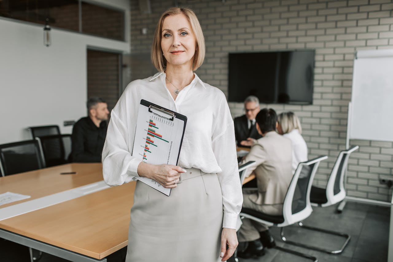 Professional businesswoman holding a clipboard during an office meeting, showcasing leadership in a corporate environment.